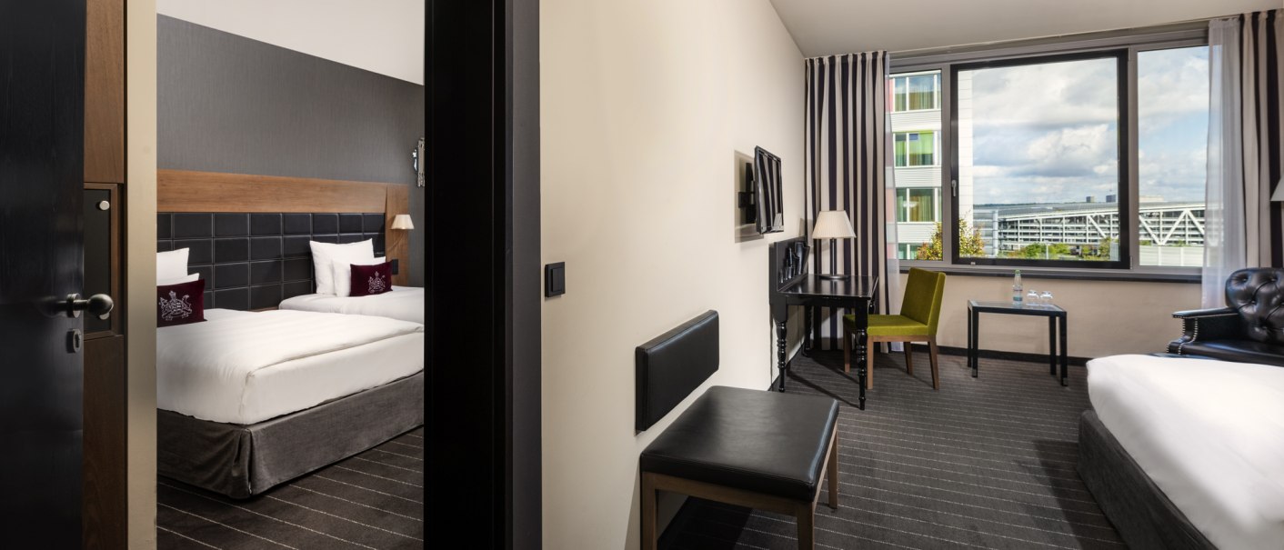 Zwei Hotelzimmer mit Verbindungstür, eines mit zwei Einzelbetten, das andere mit einem Doppelbett. Große Fenster mit Blick nach draußen., © Mövenpick Hotel Stuttgart Airport Zwei Hotelzimmer mit Verbindungstür, eines mit zwei Einzelbetten, das andere mit einem Doppelbett. Große Fenster mit Blick nach draußen., © Mövenpick Hotel Stuttgart Airport