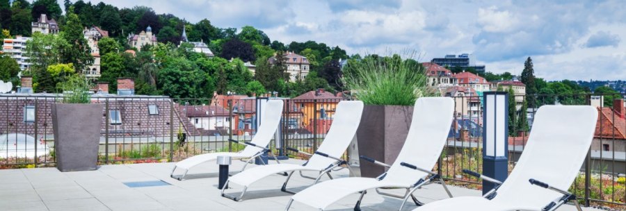 Roof terrace with white sun loungers, plants and a view of green hills and houses in the background., © Park Inn by Radisson Stuttgart Roof terrace with white sun loungers, plants and a view of green hills and houses in the background., © Park Inn by Radisson Stuttgart