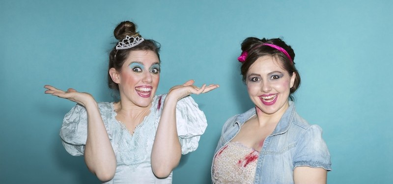 Zwei Frauen mit auff&auml;lligem Make-up und Kost&uuml;men posieren vor einem blauen Hintergrund. Eine h&auml;lt eine Flasche, beide wirken ausgelassen., &copy; Renitenztheater Stuttgart e.V.