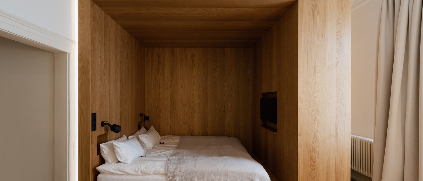 Modernes Schlafzimmer mit Holzverkleidung, eingebautem Bett und kleinem Fernseher. Minimalistisches Design mit warmen Holzt&ouml;nen und schlichter Beleuchtung., &copy; Peter Oliver Wolff / DAS EDITH