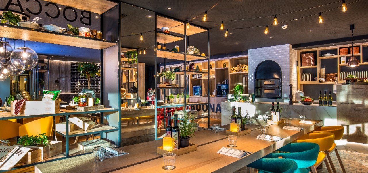 Modernes Restaurant mit Holztischen, bunten Stühlen und offener Küche. Gemütliche Beleuchtung und dekorative Pflanzen schaffen eine einladende Atmosphäre., © Park Inn by Radisson Stuttgart Modernes Restaurant mit Holztischen, bunten Stühlen und offener Küche. Gemütliche Beleuchtung und dekorative Pflanzen schaffen eine einladende Atmosphäre., © Park Inn by Radisson Stuttgart