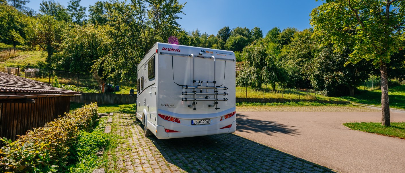 Ein Wohnmobil steht auf einem gepflasterten Stellplatz, umgeben von grünen Bäumen und sonnigem Wetter., © Stuttgart-Marketing GmbH, Thomas Niedermüller