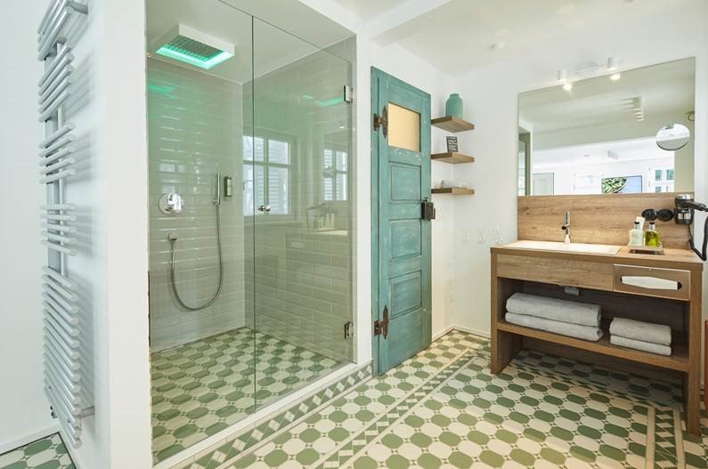 Modernes Badezimmer mit Glasdusche, gr&uuml;nem Fliesenboden, Holzwaschtisch und t&uuml;rkisfarbener T&uuml;r. Handt&uuml;cher und Pflegeprodukte sind bereitgestellt., &copy; Hotel Restaurant Bachofer