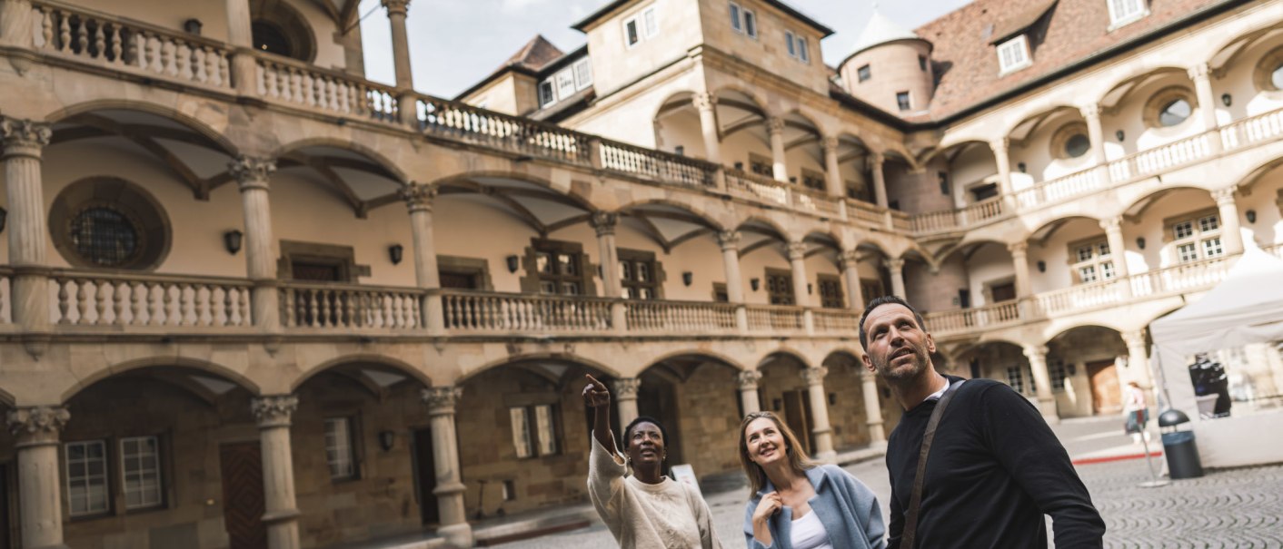 Three people stand in the inner courtyard of the Württemberg State Museum and look upwards. The inner courtyard is surrounded by arcades and historic buildings., © Stuttgart-Marketing GmbH, wpsteinheisser Three people stand in the inner courtyard of the Württemberg State Museum and look upwards. The inner courtyard is surrounded by arcades and historic buildings., © Stuttgart-Marketing GmbH, wpsteinheisser