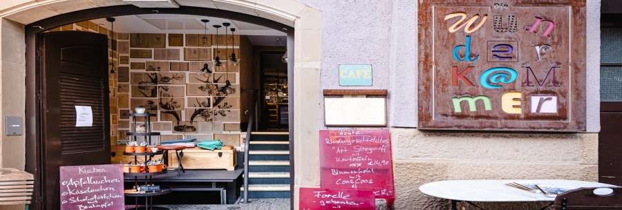 Entrance to the Wunderkammer with decorative walls, colorful sign and menus. Inviting atmosphere with café charm., © by Canto