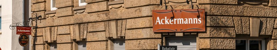 Eckgeb&auml;ude mit dem Schild 'Ackermanns' an der Fassade. Stra&szlig;enschilder f&uuml;r Bebelstr. und Schwabstr. sind sichtbar, ebenso mehrere Werbeplakate., &copy; SMG, Sarah Schmid