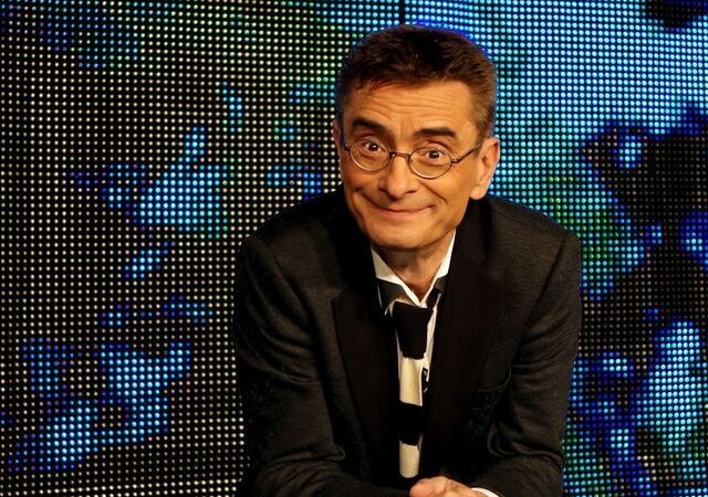 Ein Mann mit Brille und Anzug lehnt sich l&auml;chelnd auf einen durchsichtigen W&uuml;rfel vor einem bunten, digitalen Hintergrund., &copy; SKS Michael Russ GmbH