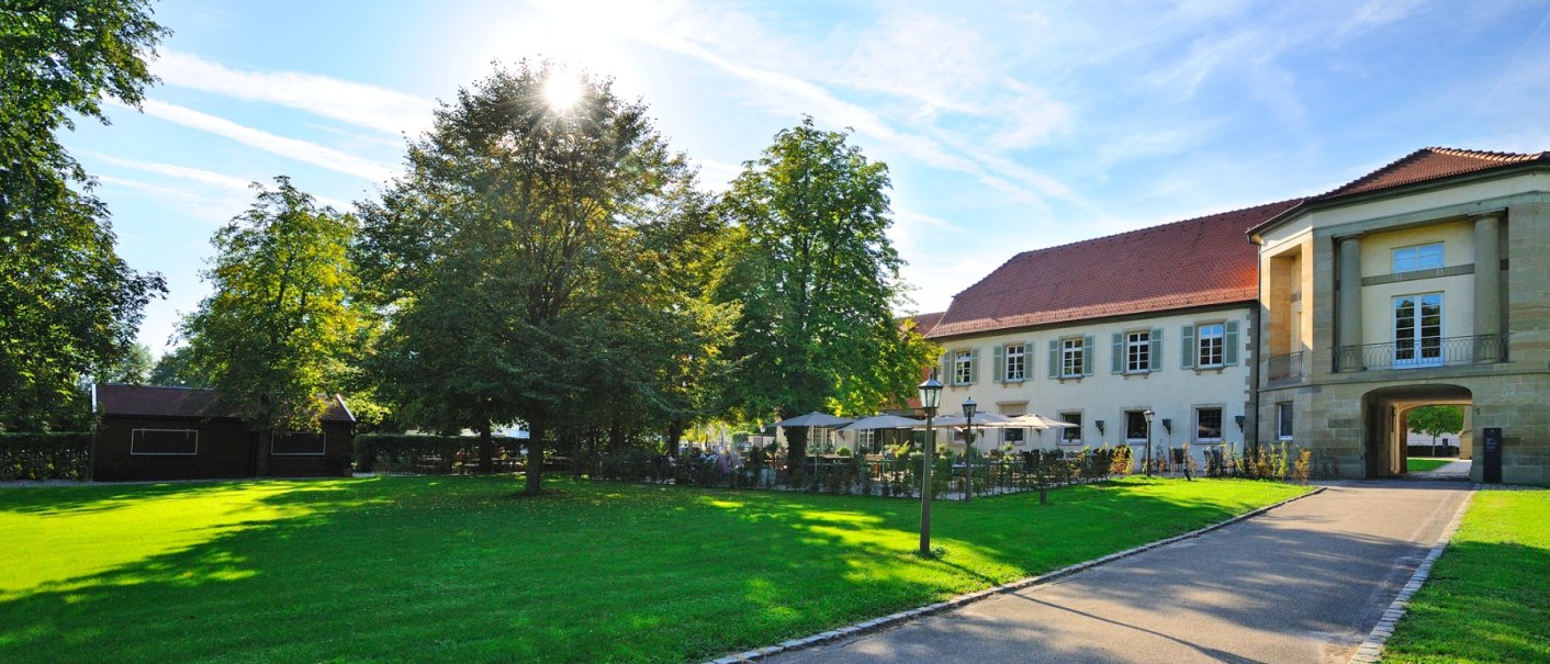 Elegant building with terrace and sunshades, surrounded by green lawns and trees in sunny weather., © Schlosshotel Monrepos Elegant building with terrace and sunshades, surrounded by green lawns and trees in sunny weather., © Schlosshotel Monrepos