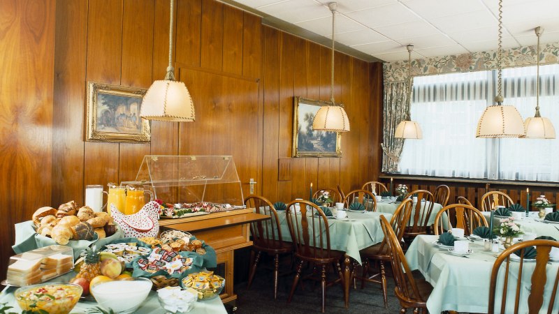 Frühstücksraum mit gedeckten Tischen, Holzstühlen und einem Buffet mit Brötchen, Obst und Saft. Holzwände und hängende Lampen schaffen eine gemütliche Atmosphäre., © Hotel Find Frühstücksraum mit gedeckten Tischen, Holzstühlen und einem Buffet mit Brötchen, Obst und Saft. Holzwände und hängende Lampen schaffen eine gemütliche Atmosphäre., © Hotel Find