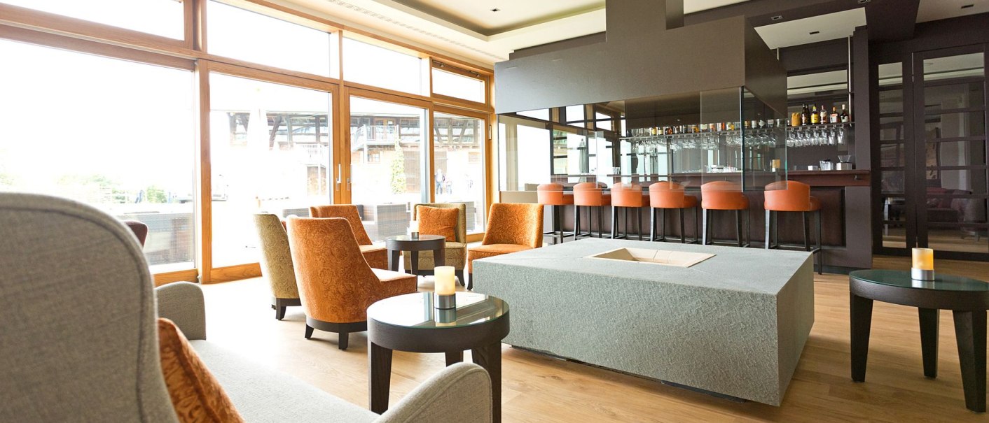 Moderne Hotelbar mit eleganten Sesseln, einem großen Kamin und einer gut ausgestatteten Theke. Große Fenster lassen viel Licht herein., © Achalm. Hotel GmbH & Co. KG Moderne Hotelbar mit eleganten Sesseln, einem großen Kamin und einer gut ausgestatteten Theke. Große Fenster lassen viel Licht herein., © Achalm. Hotel GmbH & Co. KG
