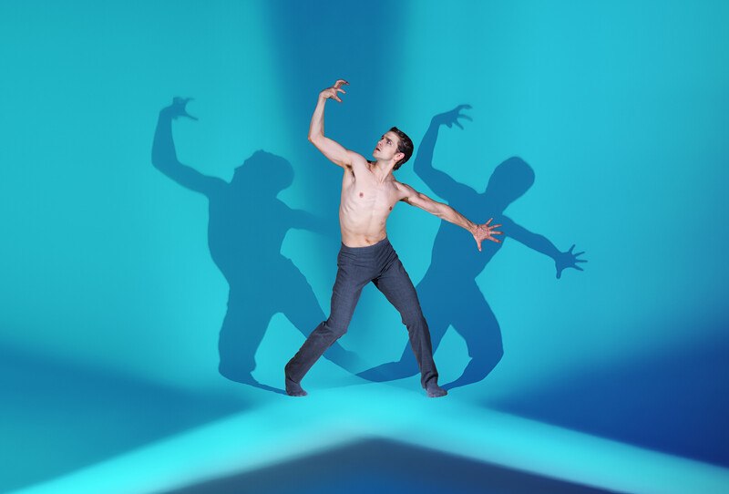 Ein T&auml;nzer in einer dynamischen Pose vor einem blauen Hintergrund. Mehrere Schatten verst&auml;rken den dramatischen Effekt., &copy; W&uuml;rttembergische Staatstheater Stuttgart