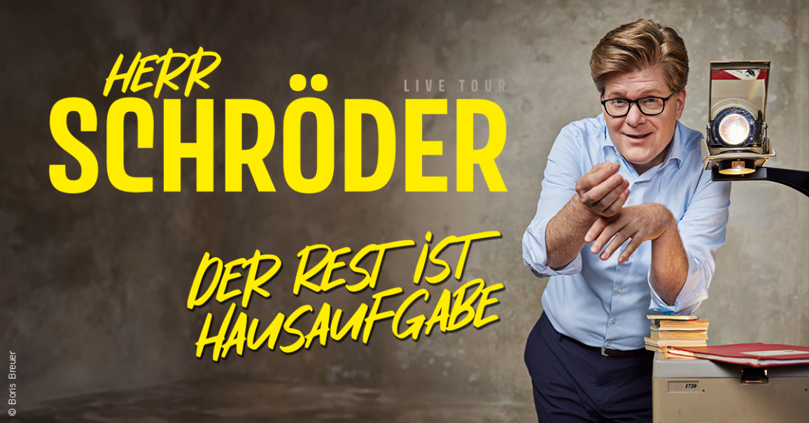 Ein Mann in einem blauen Hemd steht neben einem Overheadprojektor und l&auml;chelt. Der Text 'Herr Schr&ouml;der - Der Rest ist Hausaufgabe' ist prominent dargestellt., &copy; links im Bild