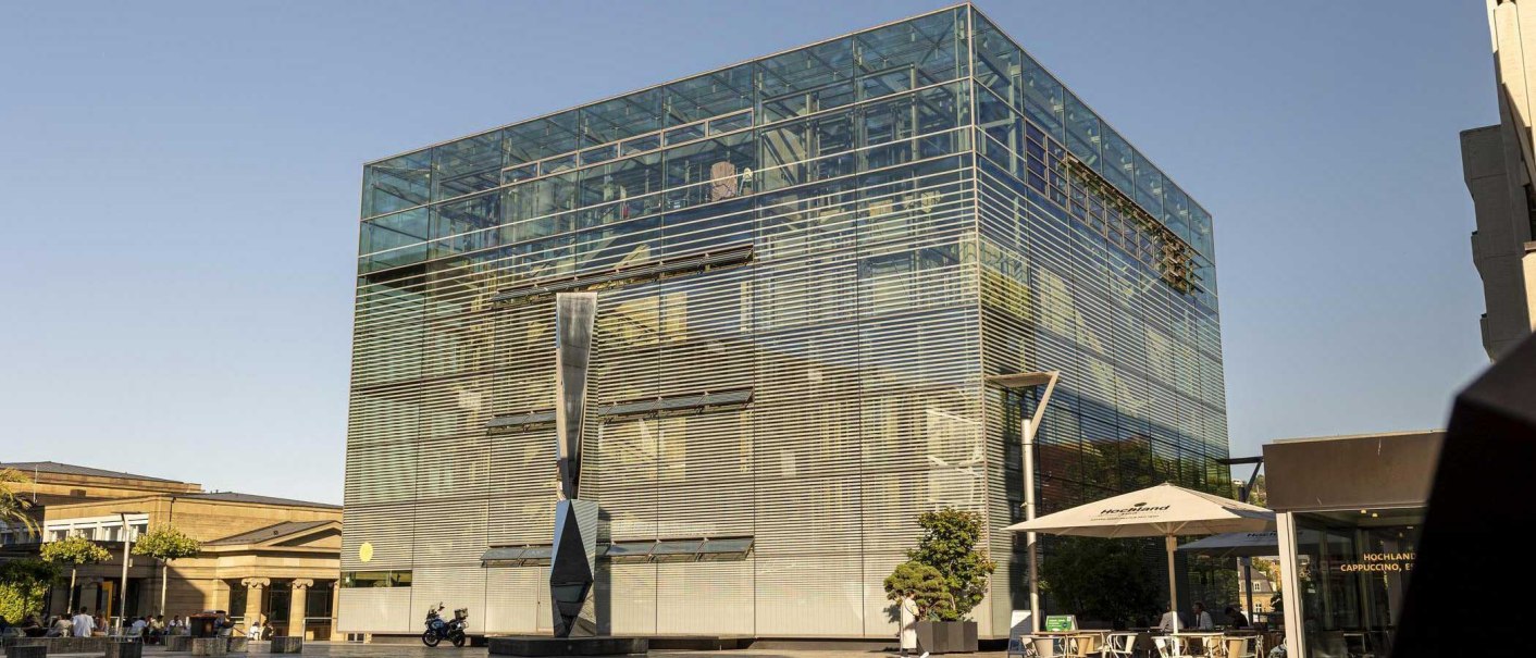 The art museum in Stuttgart with its modern glass façade and a sculpture in front of it, in sunny weather on Kleiner Schlossplatz., © Stuttgart Marketing GmbH, Sarah Schmid The art museum in Stuttgart with its modern glass façade and a sculpture in front of it, in sunny weather on Kleiner Schlossplatz., © Stuttgart Marketing GmbH, Sarah Schmid