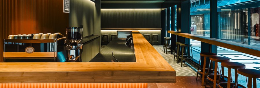 Moderne Bar mit Holztresen, Hockern und stilvoller Beleuchtung in der Shobu Calwer Passage. Dunkle W&auml;nde und geometrische Deckenmuster., &copy; Blackbook Studios