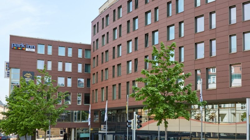 Das Park Inn by Radisson Stuttgart zeigt eine moderne Fassade mit vielen Fenstern. Vor dem Gebäude stehen grüne Bäume., © Park Inn by Radisson Stuttgart