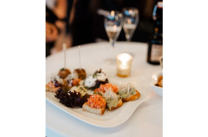 Vorspeisenteller mit Canap&eacute;s auf wei&szlig;em Tisch, zwei Gl&auml;ser und Kerze im Hintergrund, romantische Atmosph&auml;re., &copy; Cool-Tours StattReisen
