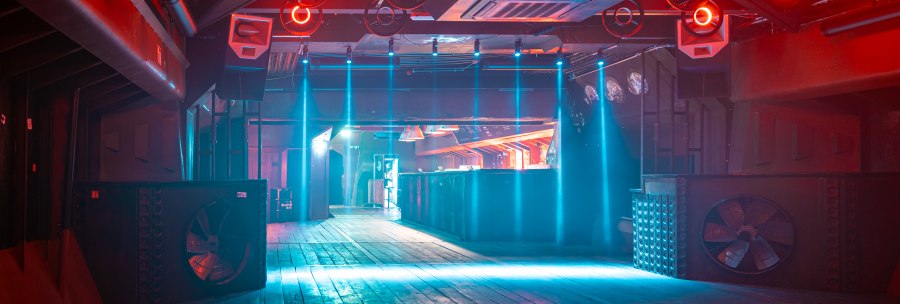 Empty nightclub with wooden floor, red and blue lighting. Round lights hang from the ceiling and a bar can be seen in the background., © SMG Stuttgart Marketing GmbH, Sarah Schmid Empty nightclub with wooden floor, red and blue lighting. Round lights hang from the ceiling and a bar can be seen in the background., © SMG Stuttgart Marketing GmbH, Sarah Schmid