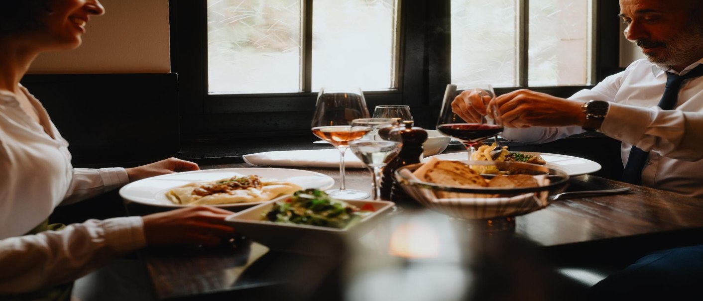 Zwei Personen genie&szlig;en ein Essen in einem Restaurant. Auf dem Tisch stehen Wein, Brot und Salat. Die Atmosph&auml;re wirkt gem&uuml;tlich und elegant., &copy; Stuttgart-Marketing GmbH, Alwin Maigler