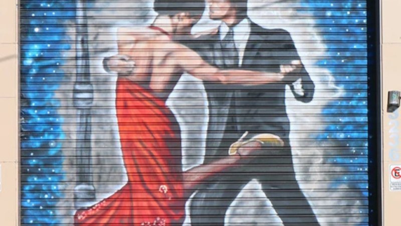 Wall painting shows a couple tangoing under a lantern. The woman is wearing a red dress, the man a suit and hat. Background in blue and white., &copy; Stuttgarter Kammerorchester e.V.