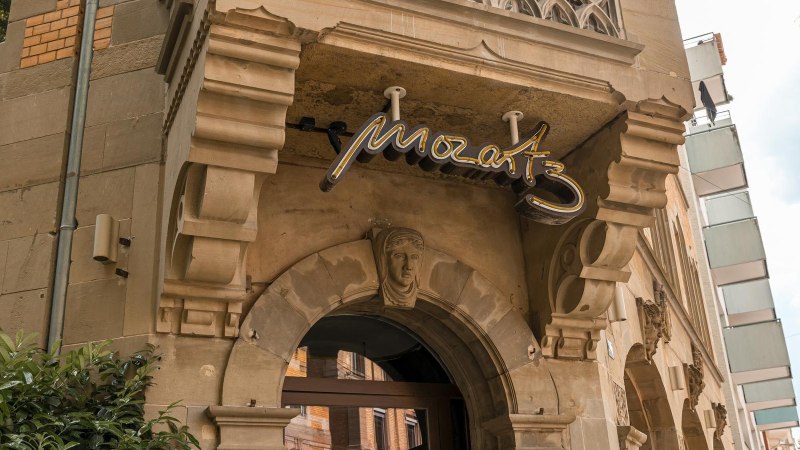 Eingang eines historischen Gebäudes mit dem Schriftzug 'Mozart3' über dem Torbogen. Verzierungen und Pflanzen sind sichtbar., © SMG, Sarah Schmid