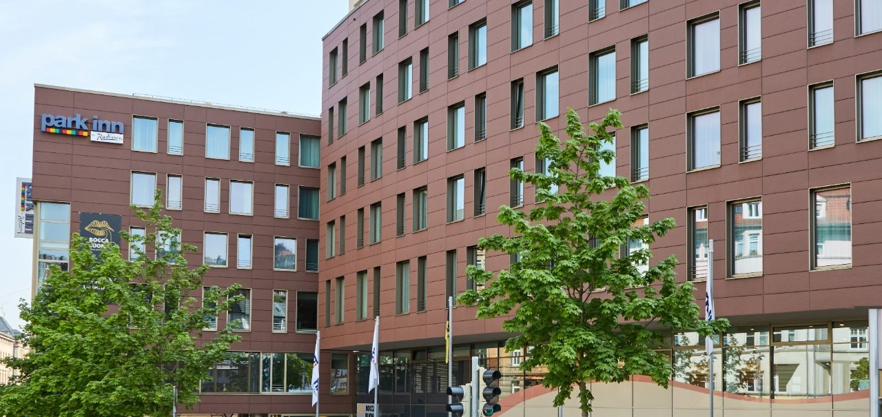 Das Park Inn by Radisson Stuttgart zeigt eine moderne Fassade mit vielen Fenstern. Vor dem Gebäude stehen grüne Bäume., © Park Inn by Radisson Stuttgart