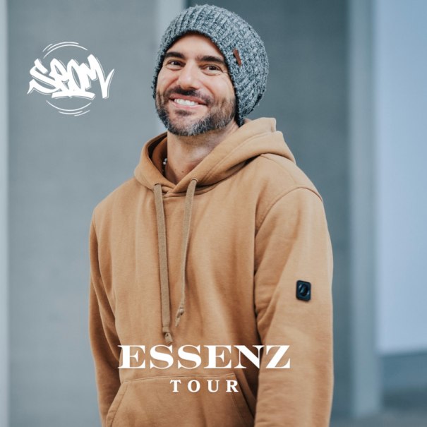 Man with gray cap and brown hoodie smiling. Lettering 'ESSENZ TOUR' in the foreground. Background blurred., &copy; SEOM Music GmbH