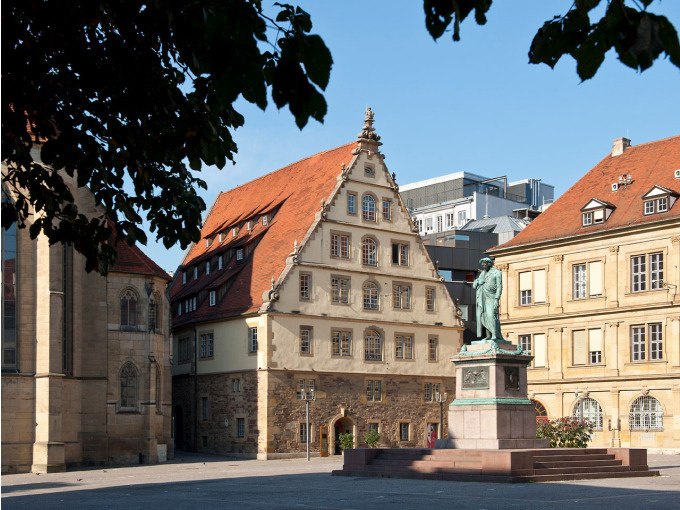 Ein historischer Platz mit einer Statue im Vordergrund, umgeben von alten Gebäuden mit roten Dächern, im Sonnenschein., © Landesmuseum Württemberg Ein historischer Platz mit einer Statue im Vordergrund, umgeben von alten Gebäuden mit roten Dächern, im Sonnenschein., © Landesmuseum Württemberg