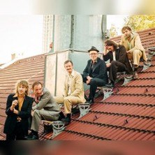 Six people sit casually on a sloping tiled roof and look relaxed into the camera., &copy; links im Bild