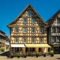 Half-timbered houses on Murrhardt&rsquo;s market square under a clear blue sky. Tables and chairs from a caf&eacute; are set up in front of the buildings., &copy; SMG Stuttgart Marketing GmbH - Sarah Schmid