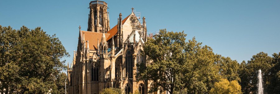 St. John's Church on the Feuersee, surrounded by trees, with a fountain in the foreground under a clear sky., &copy; SMG Stuttgart Marketing GmbH - Sarah Schmid
