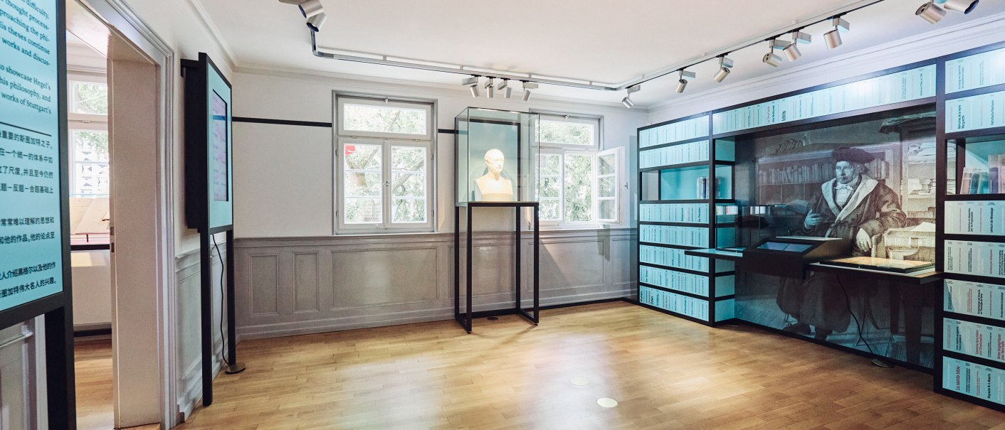 Interior view of the permanent exhibition in the Hegel House. A bust stands in a glass case, next to it a large wall display with historical illustrations., © JuliaOchs