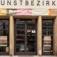 Entrance to the art district with a banner for the exhibition 'Summer reloaded'. The façade is made of stone with large windows., © Stuttgart-Marketing GmbH, Sarah Schmid Entrance to the art district with a banner for the exhibition 'Summer reloaded'. The façade is made of stone with large windows., © Stuttgart-Marketing GmbH, Sarah Schmid