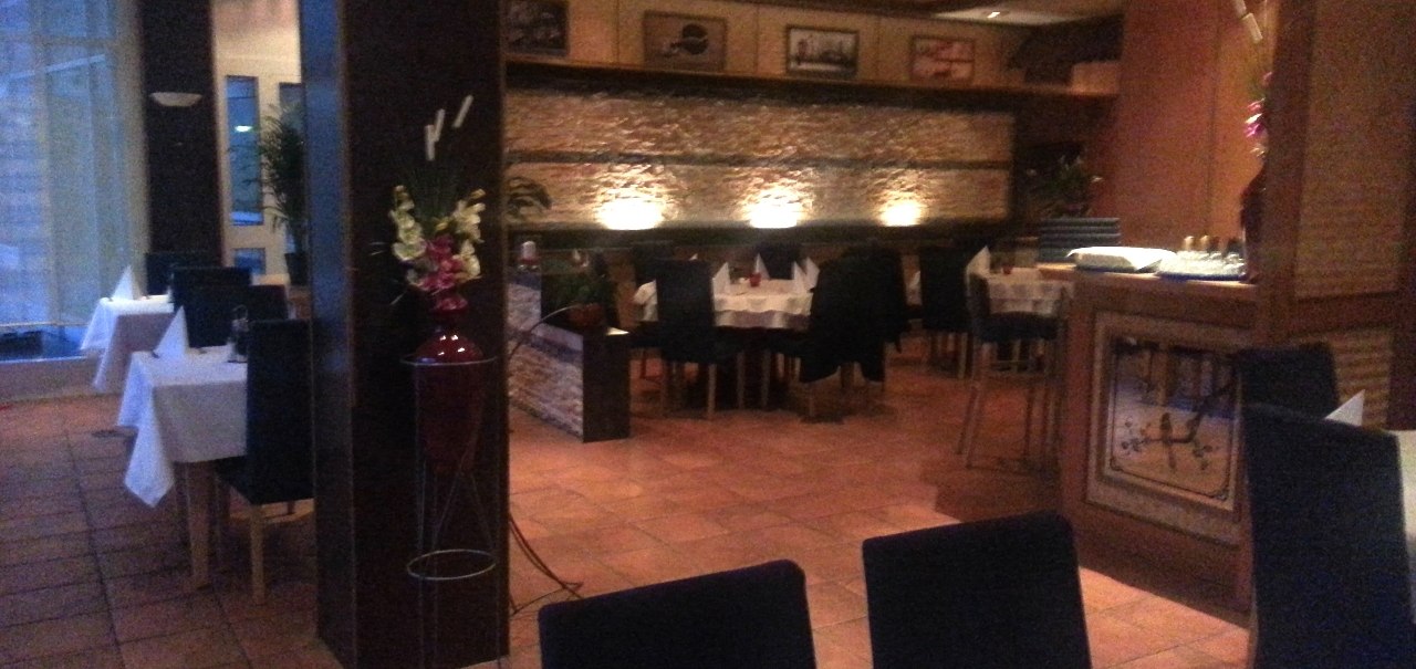 Ein stilvoll eingerichtetes Restaurant mit gedeckten Tischen, dunklen St&uuml;hlen und ged&auml;mpfter Beleuchtung. An den W&auml;nden sind Bilder und Dekorationen., &copy; Restaurant Akropolis