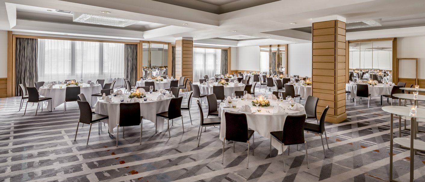 Elegant ballroom with round tables, white tablecloths and floral arrangements, ready for an event., © Stuttgart Marriott Hotel Sindelfingen Elegant ballroom with round tables, white tablecloths and floral arrangements, ready for an event., © Stuttgart Marriott Hotel Sindelfingen