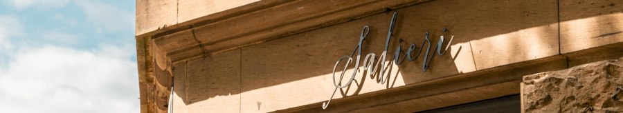 Facade of a building with the lettering 'Salieri' and a surveillance camera. The sun casts shadows on the sand-colored wall., &copy; SMG, Sarah Schmid
