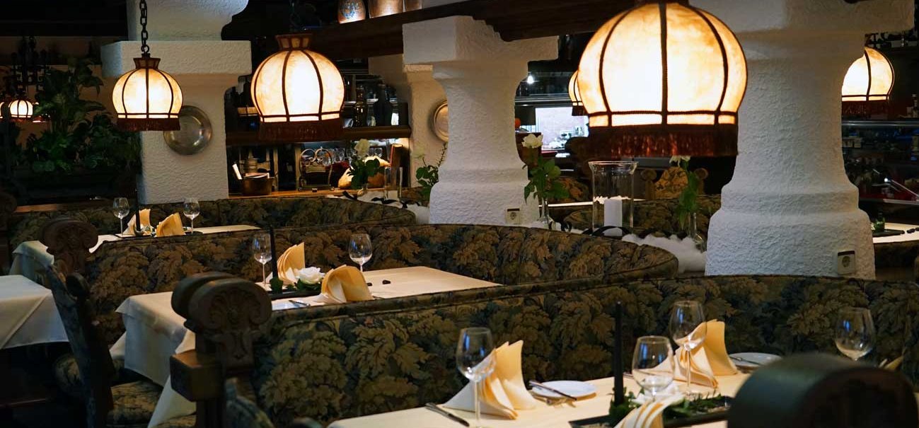 Ein gemütliches Restaurant mit rustikaler Einrichtung, warmem Licht und dekorativen Lampen. Die Tische sind elegant gedeckt mit Gläsern und Servietten., © Hotel & Restaurant Beurener Hof Ein gemütliches Restaurant mit rustikaler Einrichtung, warmem Licht und dekorativen Lampen. Die Tische sind elegant gedeckt mit Gläsern und Servietten., © Hotel & Restaurant Beurener Hof