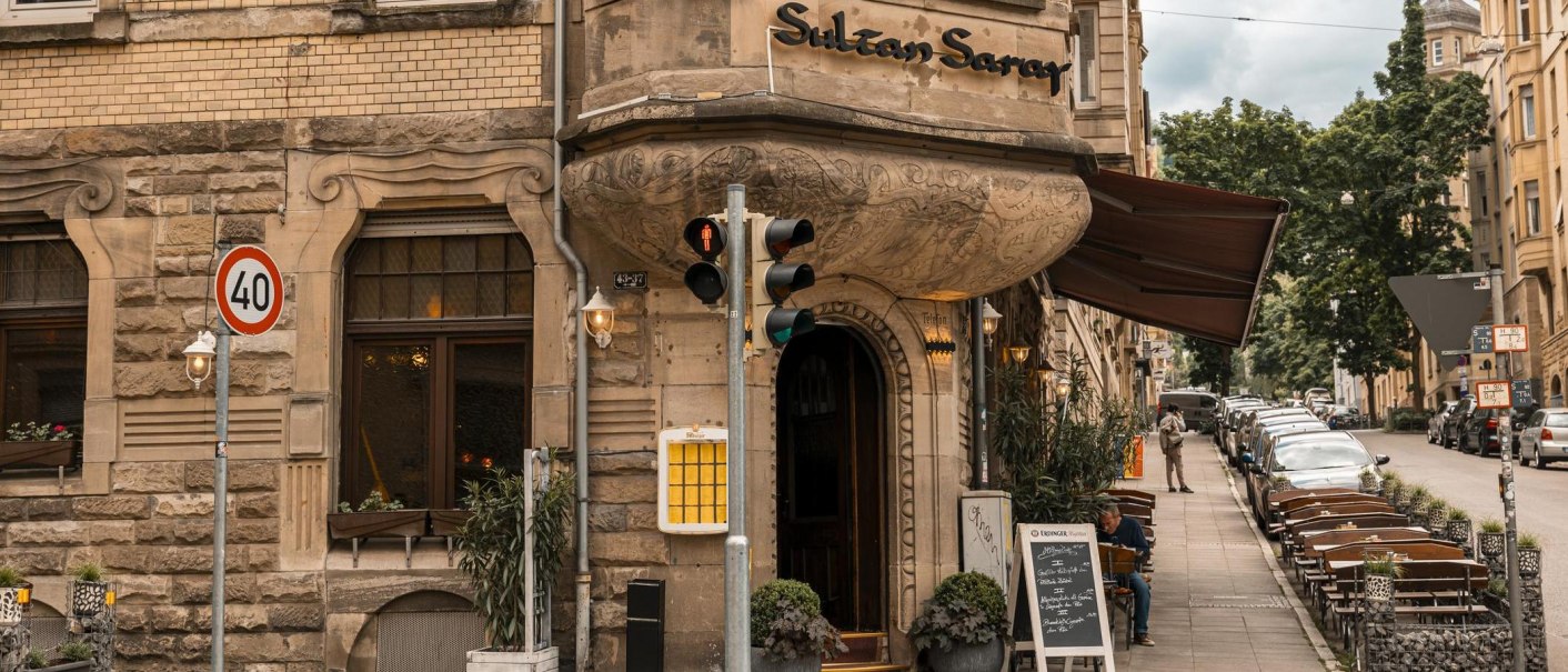 A restaurant called Sultan Saray in a historic building. There are tables on the sidewalk in front of the entrance. A traffic sign indicates 40 km/h., © SMG Stuttgart Marketing GmbH - Sarah Schmid A restaurant called Sultan Saray in a historic building. There are tables on the sidewalk in front of the entrance. A traffic sign indicates 40 km/h., © SMG Stuttgart Marketing GmbH - Sarah Schmid