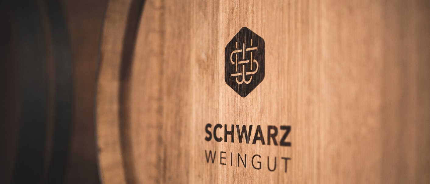 Wooden barrel with the logo and lettering 'Schwarz Weingut', close-up., © Weingut Schwarz Wooden barrel with the logo and lettering 'Schwarz Weingut', close-up., © Weingut Schwarz
