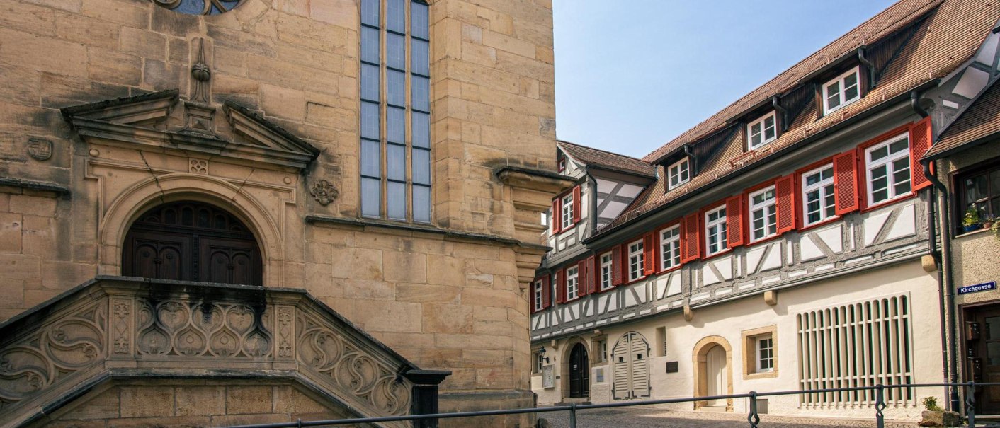 Historic buildings in Waldenbuch with half-timbered and sandstone façades. On the left an old building with ornate stone elements, on the right a half-timbered house with red shutters., © Stuttgart-Marketing GmbH, Sarah Schmid