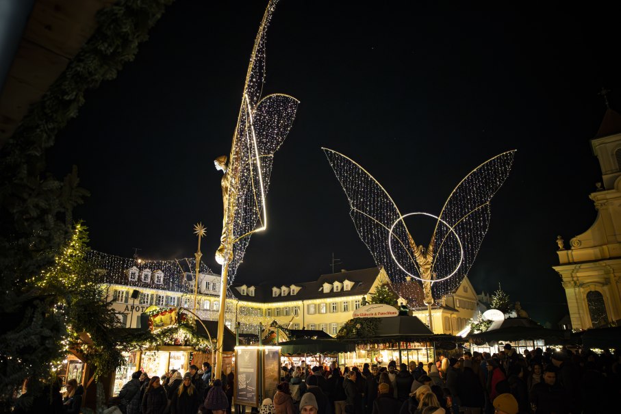 The Ludwigsburg Baroque Christmas market on the market square at night, illuminated large angel figures and stalls. Some visitors bustle around the square., © Stuttgart Marketing GmbH, Sarah Schmid