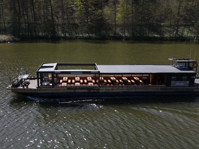 Ein Flussschiff mit offenen Sitzbereichen f&auml;hrt auf einem Fluss, umgeben von B&auml;umen., &copy; Cool-Tours StattReisen