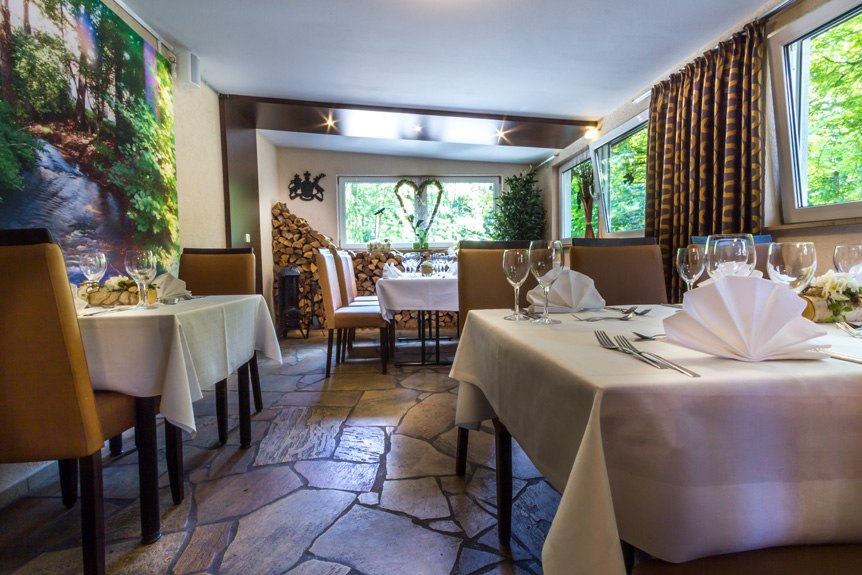An elegant breakfast room with set tables, white tablecloths, and large windows overlooking the greenery., &copy; Kulinarium an der Glems