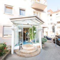 Hoteleingang mit Glasüberdachung und runden Stufen, umgeben von Autos und Pflanzen. Gebäude mit mehreren Fenstern im Hintergrund., © ARNOTEL GmbH Hoteleingang mit Glasüberdachung und runden Stufen, umgeben von Autos und Pflanzen. Gebäude mit mehreren Fenstern im Hintergrund., © ARNOTEL GmbH