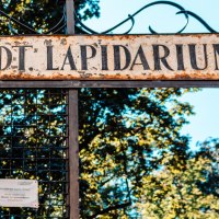 Eingang zum Städtischen Lapidarium mit einem alten, verwitterten Schild und einer Steinskulptur. Im Hintergrund sind Bäume zu sehen., © Stuttgart Marketing GmbH, Sarah Schmid Eingang zum Städtischen Lapidarium mit einem alten, verwitterten Schild und einer Steinskulptur. Im Hintergrund sind Bäume zu sehen., © Stuttgart Marketing GmbH, Sarah Schmid