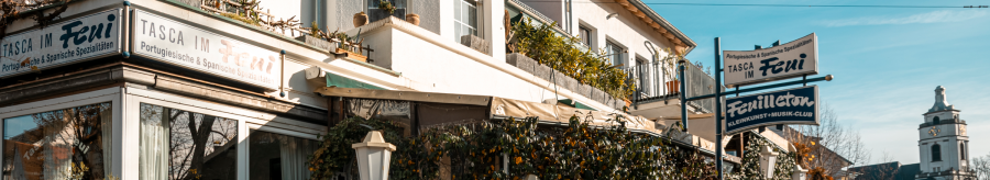 Ein Restaurant mit dem Namen 'Tasca im Feui', das portugiesische und spanische Spezialitäten anbietet. Daneben ein Schild für 'Feuilleton', einen Kleinkunst- und Musikclub., © Stuttgart-Marketing GmbH, Sarah Schmid Ein Restaurant mit dem Namen 'Tasca im Feui', das portugiesische und spanische Spezialitäten anbietet. Daneben ein Schild für 'Feuilleton', einen Kleinkunst- und Musikclub., © Stuttgart-Marketing GmbH, Sarah Schmid