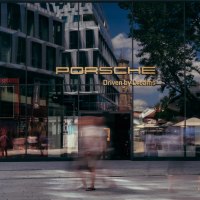 Glasfassade des Porsche Brand Stores mit Jubil&auml;umslogo '75 Jahre 1948-2023'. Menschen gehen vorbei, Geb&auml;ude und B&auml;ume spiegeln sich im Glas., &copy; Porsche AG