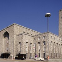Der Hauptbahnhof Stuttgart mit seinem markanten Uhrturm und Mercedes-Stern, umgeben von Autos und Bäumen, unter einem klaren blauen Himmel., © Stuttgart-Marketing GmbH Der Hauptbahnhof Stuttgart mit seinem markanten Uhrturm und Mercedes-Stern, umgeben von Autos und Bäumen, unter einem klaren blauen Himmel., © Stuttgart-Marketing GmbH