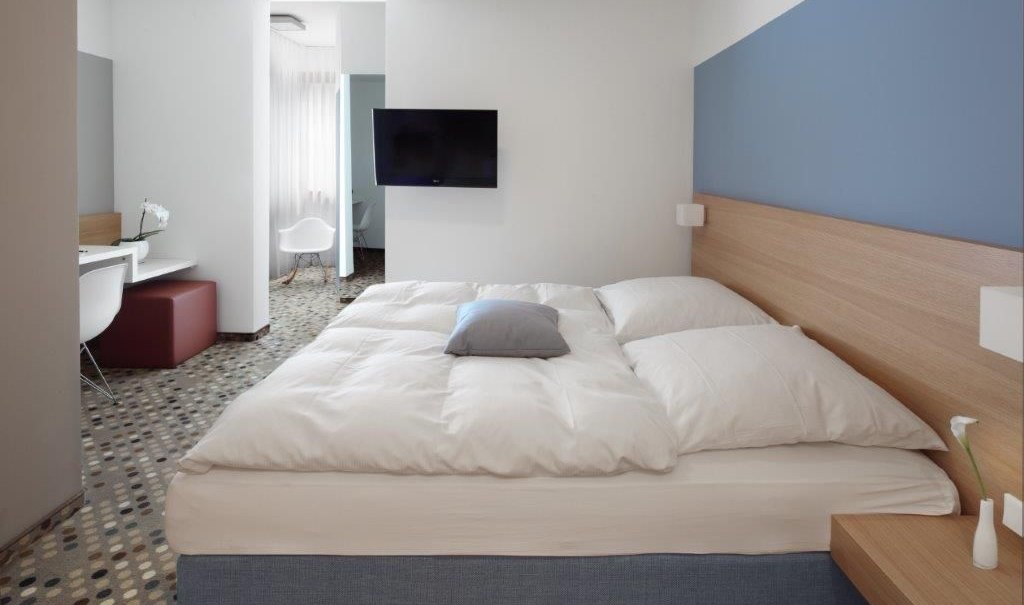 Modern double room with a large bed, a desk, a flat-screen TV, and stylish carpeting., &copy; Hotel Waldhorn