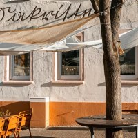 Ein Caf&eacute; mit Sonnensegeln und orangefarbenen St&uuml;hlen auf der Terrasse. Die Fassade ist wei&szlig; mit einem orangefarbenen Sockel., &copy; Stuttgart-Marketing GmbH, Sarah Schmid