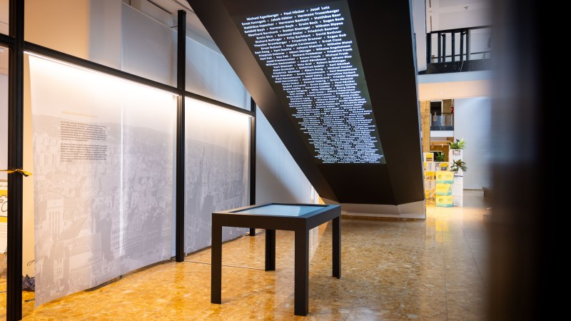 Rauminstallation im Stuttgarter Rathaus mit projizierten Namen an der Decke und einem interaktiven Tisch auf einem gl&auml;nzenden Boden., &copy; Julian Rettig